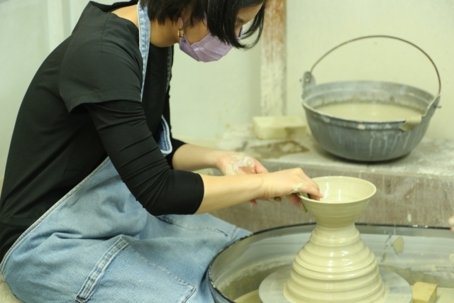 ろくろで陶芸作品を作る女性