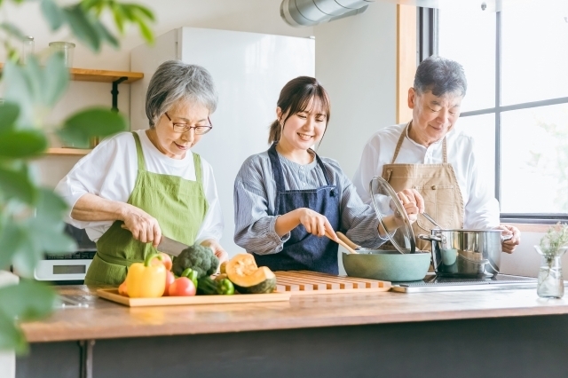 キッチンで料理する女性と老夫婦