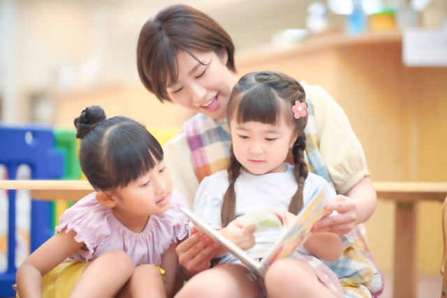 子どもに絵本を読み聞かせする保育士