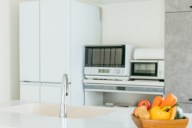 冷蔵庫やオーブンレンジが並ぶ白いキッチン