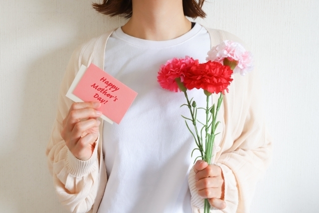 母の日の赤いカーネーションとメッセージカードを持つ女性