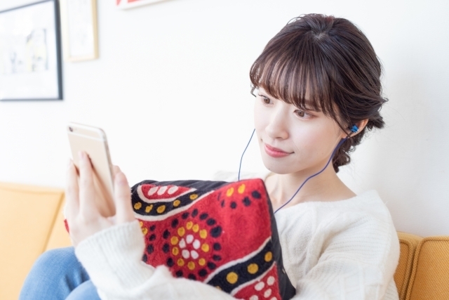 イヤホンを付けてスマホで音楽を聴く女性