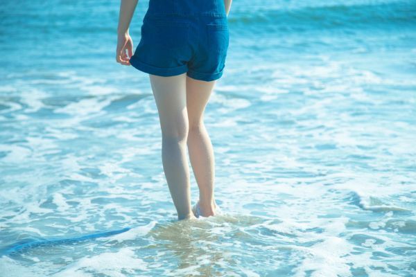 波打ち際に立つショーパン姿の女性