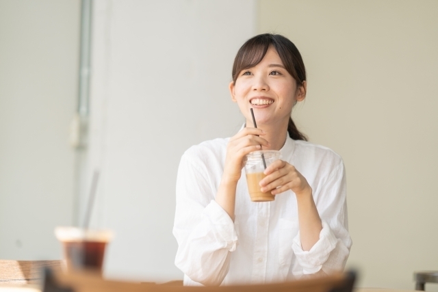 カフェで冷たいカフェラテを飲む女性